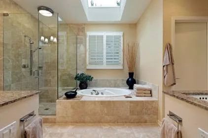 Tiled bathroom with soaking tub, glass shower, skylight, and stone vanity tops