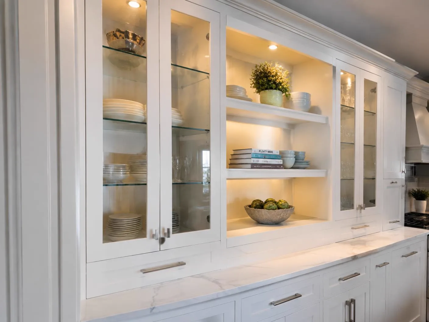 Custom white kitchen cabinetry with glass doors and lit open shelving